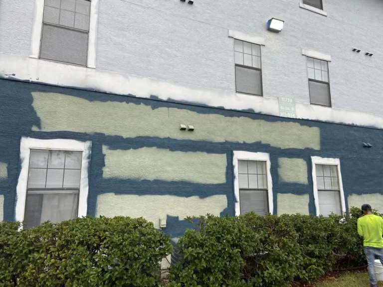 Painter working a repaired horizontal band on an occupied apartment building