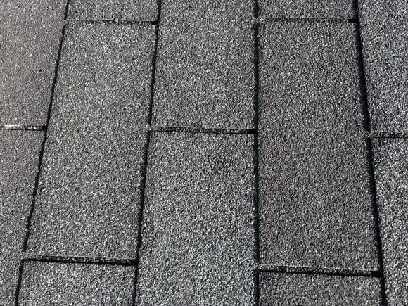 Three tab asphalt shingles on a St. Anthony roof photographed with no markup, before the impact was circled.