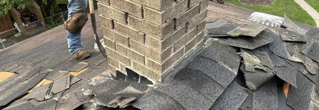 A Right Away Construction crew member on a Northeast Minneapolis roof, working beside the brick chimney.