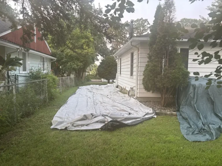 Large protective covering spread across a Minneapolis back lawn during a roof tear-off.