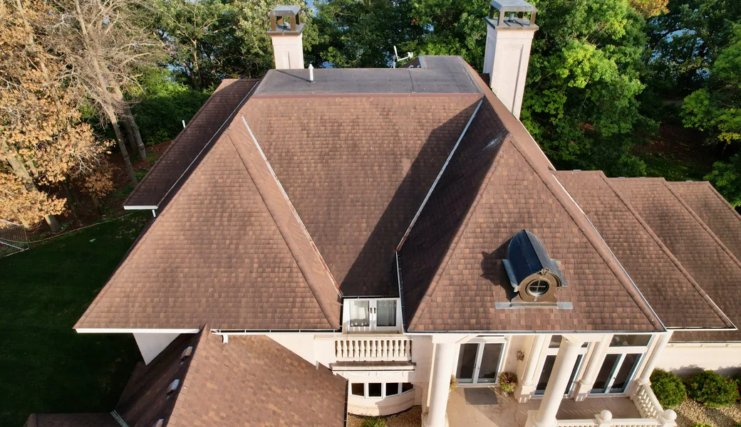 Aerial view of an aging asphalt shingle roof with chimneys, photographed before replacement