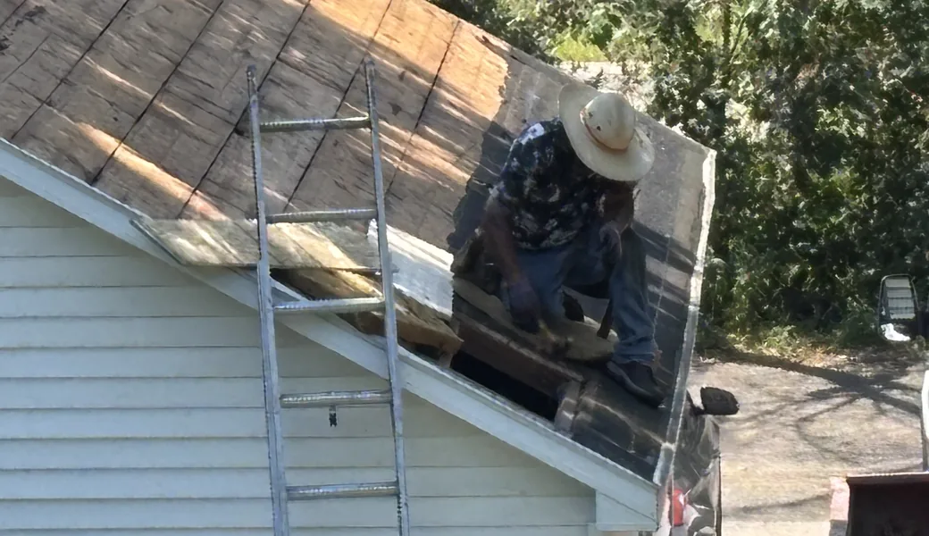 Roofer working at the gable edge during a tear-off on a Minneapolis home