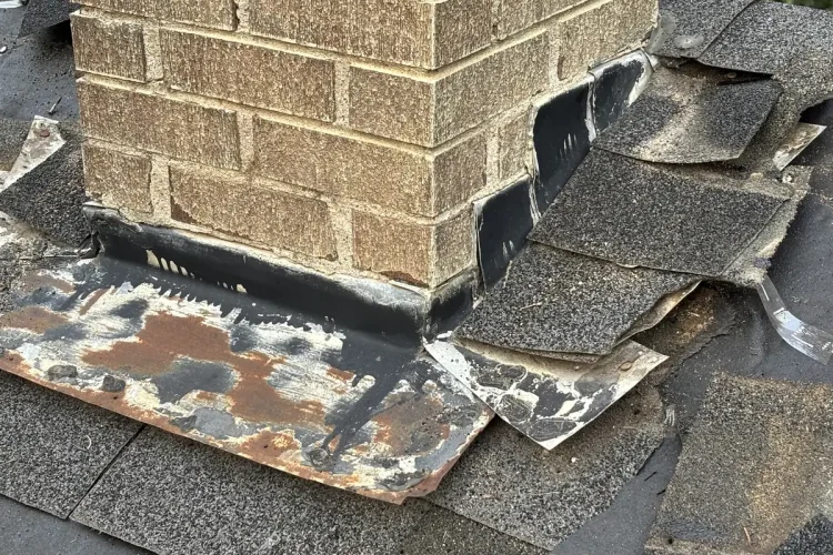 Close view of old chimney base flashing and tar patching on a Minneapolis roof.