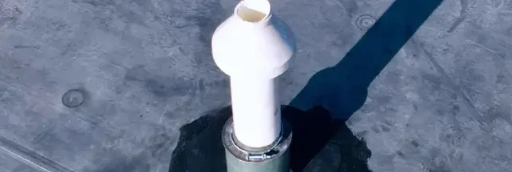 White vent pipe flashed through an EPDM membrane on a low-slope roof section