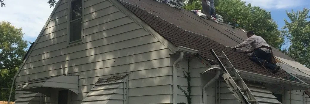Roof replacement in progress on a Blaine MN home, with a roofer at the eave