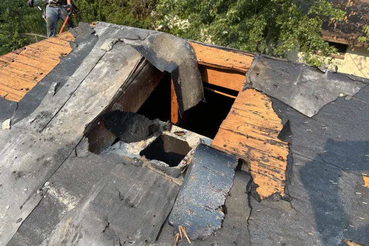 Roof tear-off in progress on a Minneapolis home with decking and an old opening exposed.