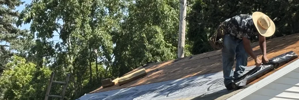 Roofer rolling out synthetic underlayment during a roof replacement in Minneapolis